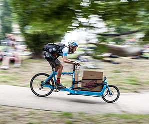 Ein Mann transportiert einen Pappkarton mit einem Lastenfahrrad.