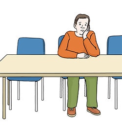Die Abbildung zeigt einen traurigen und nachdenklichen Mann, der alleine an einem Bürotisch sitzt.