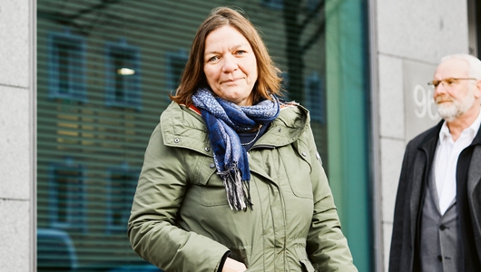 BEM-Fallmanagerin Silke Schulze und BEM-Koordinator Frank Batsch stehen vor dem Gebäude der Berliner Stadtreinigung (BSR). Schulze trägt ihre schulterlangen Haare offen sowie einen grauen Mantel und blauen Schal. Batsch hat graue Haare und Bart, trägt eine Brille und einen anthrazitfarbenen Mantel.