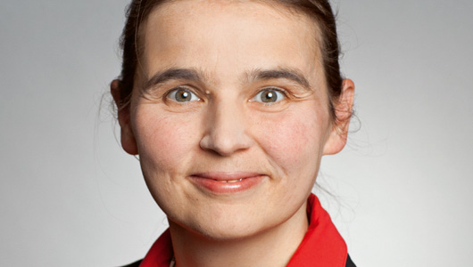 Porträt von Dr. Susanne Zöllner, Bereichsleiterin Gefahrstoffinformation – GESTIS, Institut für Arbeitsschutz der DGUV. Sie lächelt in die Kamera und trägt ihre dunkelbraunen Haare zu einem Zopf. Sie trägt eine rote Bluse und einen schwarzen Blazer.