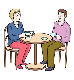 Zwei Personen sitzen an einem runden Tisch und trinken Kaffee.