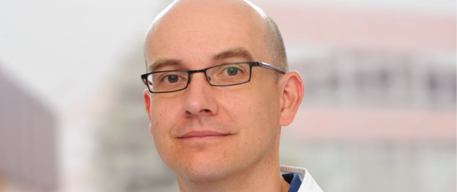 Porträt von Prof. Peter Schwenkreis vom Universitätsklinikum Bergmannsheil Bochum. Er trägt Glatze und eine Brille.