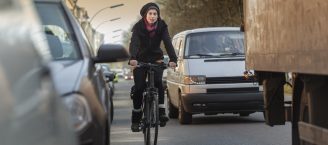 Eine Frau fährt mit dem Fahrrad durch den Stadtverkehr.