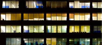 Fassade eines beleuchteten Bürogebäudes bei Nacht. Foto: Getty Images/benedek